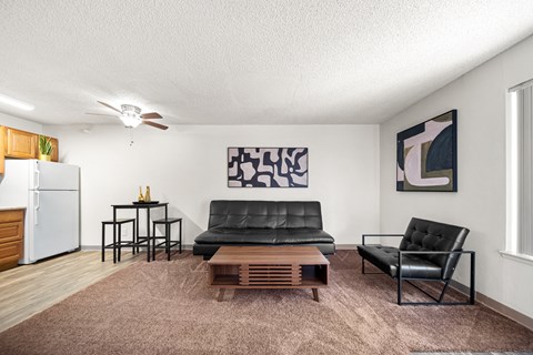 A living room with a black leather couch and a wooden coffee table.