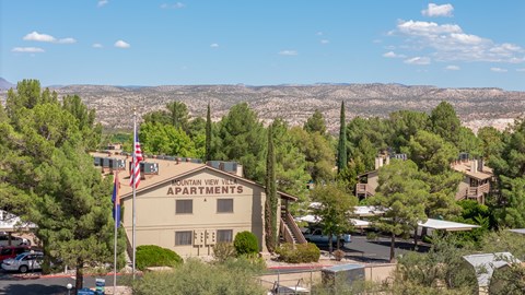 A building with the sign "Mountain View Apartments" is surrounded by trees and has an American flag flying in front of it.
