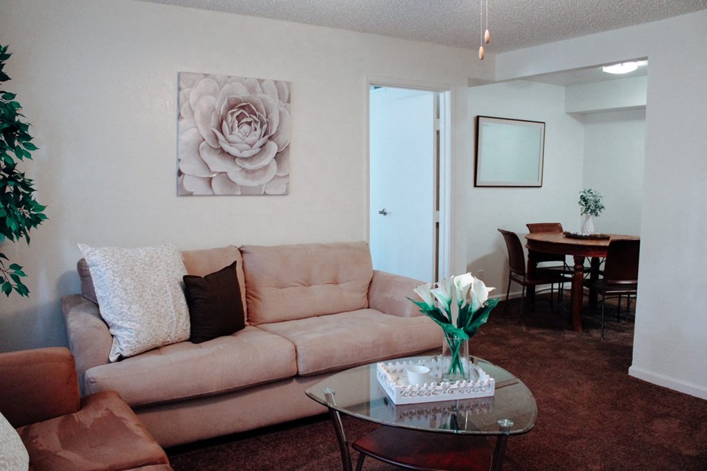 a living room with a couch and a table with a vase of flowers
