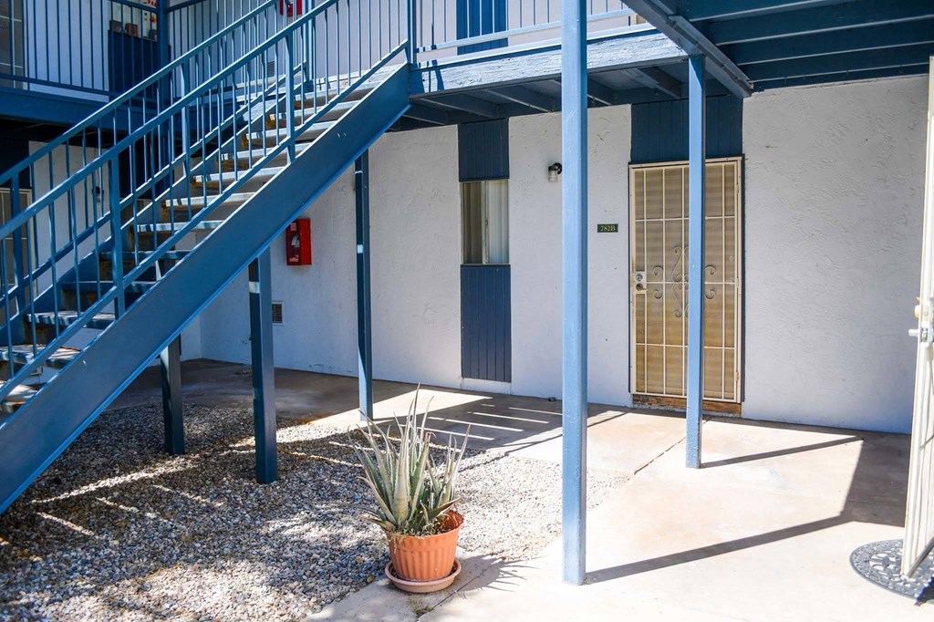 a blue and white building with a blue staircase and a potted plant in front of it