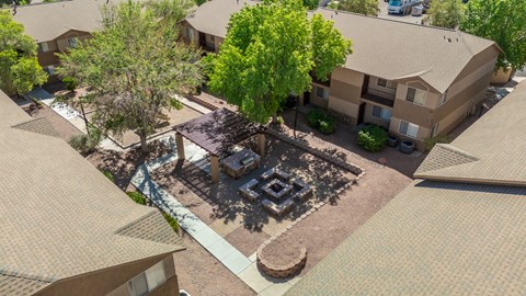 A courtyard surrounded by buildings with a firepit in the middle.
