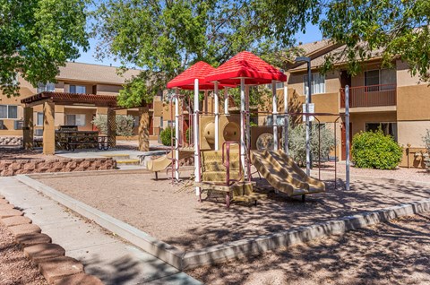 A playground with a red umbrella and a slide.