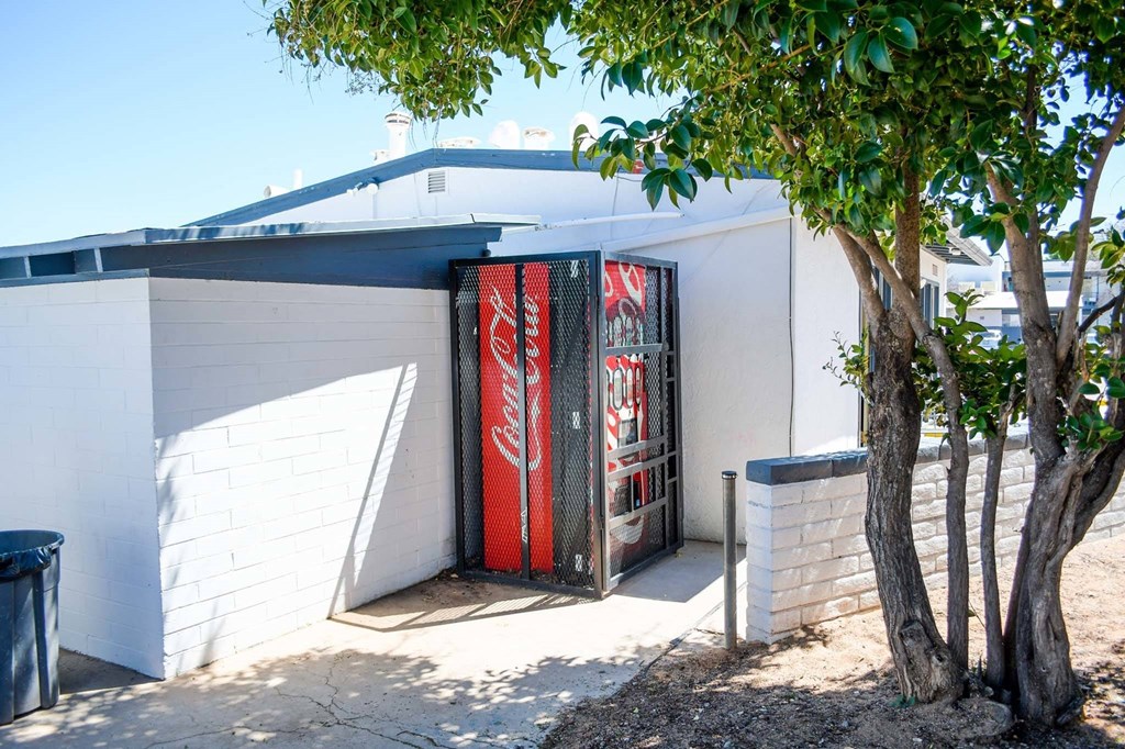a red and white coke machine in front of a white building