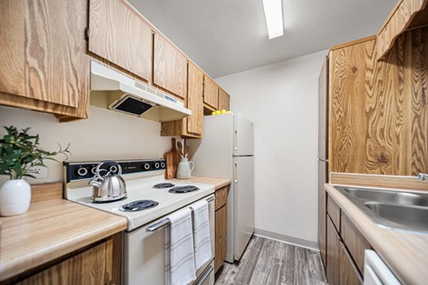 A kitchen with wooden cabinets and a white stove top oven.
