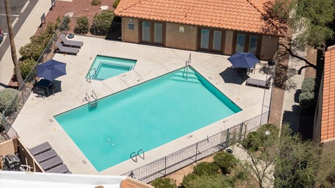 An outdoor swimming pool surrounded by a fence and trees.