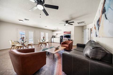 A living room with a brown leather couch and a ceiling fan.