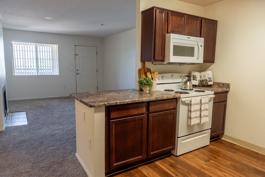 A kitchen with a white stove and wooden cabinets.