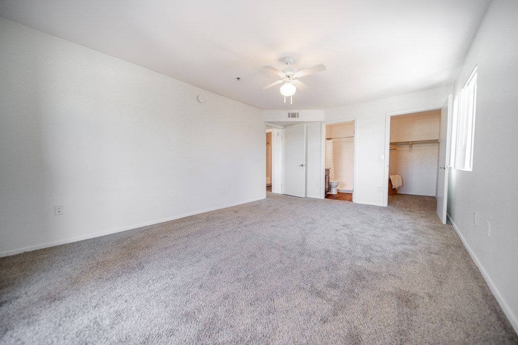 Empty room with a ceiling fan and carpeted floor.