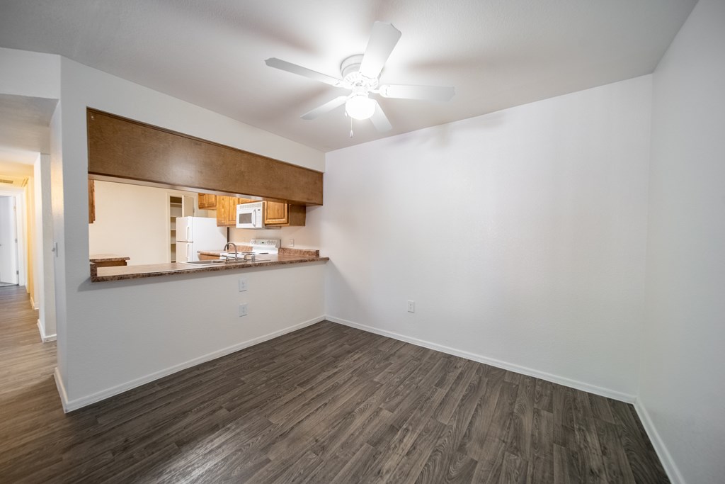 A room with a ceiling fan and wooden flooring.