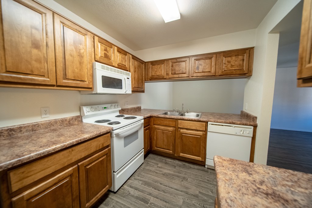 A kitchen with wooden cabinets and a white stove top oven.