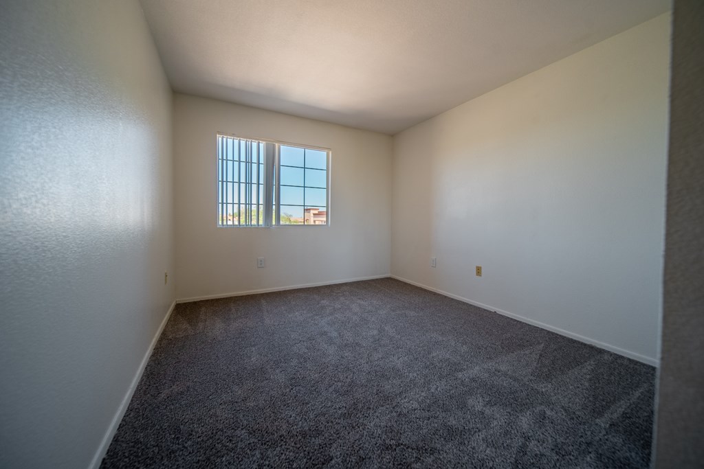 A room with a carpeted floor and a window.