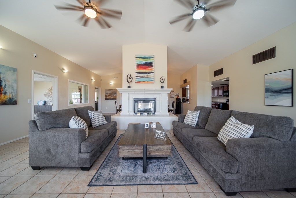 A living room with a fireplace and two grey couches.