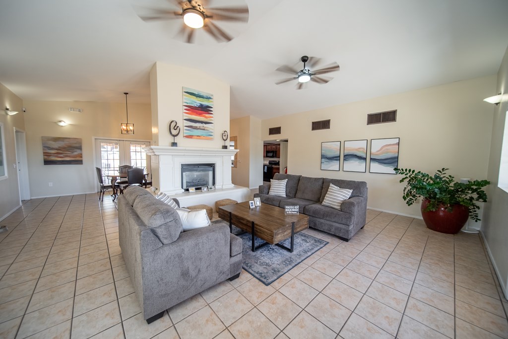 A living room with a fireplace and a ceiling fan.