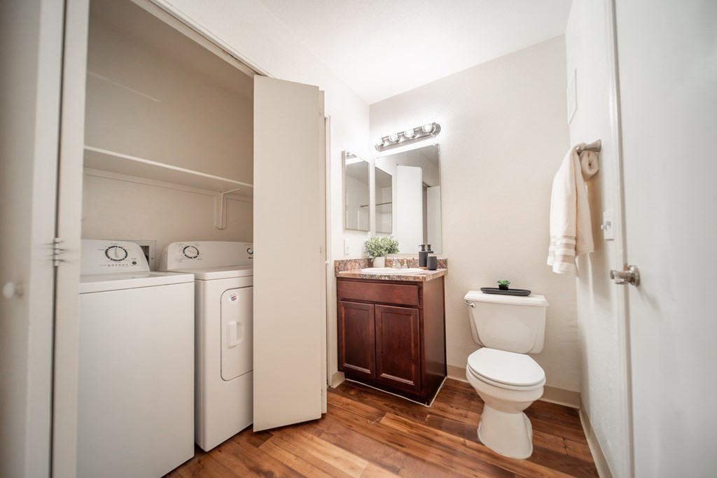 A small bathroom with a toilet, sink, and washer and dryer.