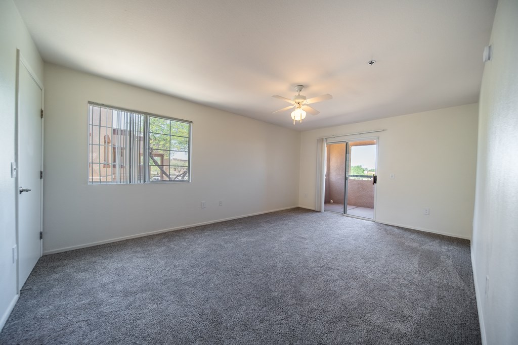 A spacious room with a carpeted floor and a ceiling fan.