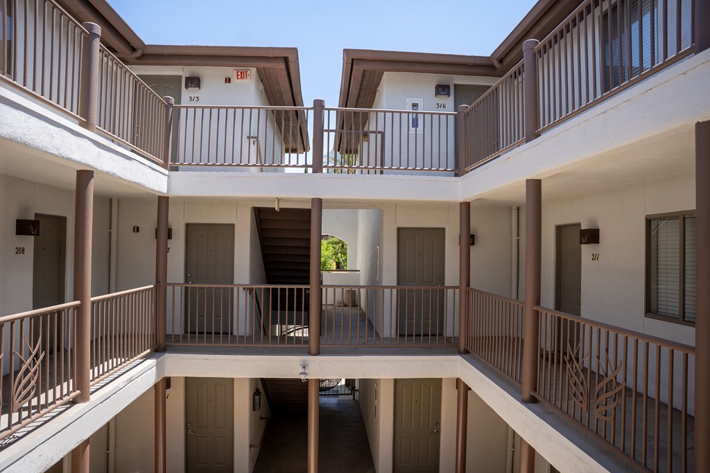 A view of a balcony of a building with a tree in the background.