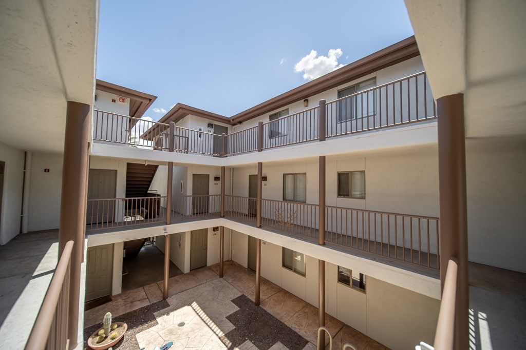 A courtyard surrounded by balconies with a blue sky in the background.