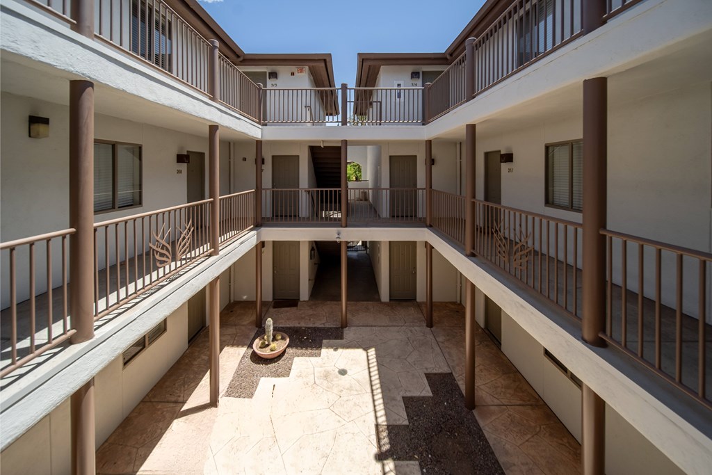 A courtyard surrounded by balconies with a small tree in the middle.