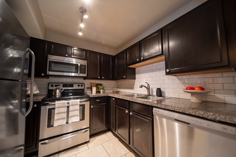 A modern kitchen with dark brown cabinets and stainless steel appliances.
