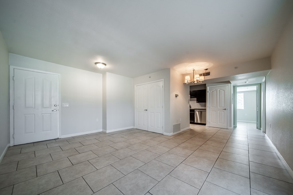 A spacious room with tiled flooring and white walls.