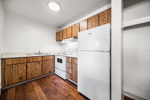 A white refrigerator in a kitchen with wooden cabinets.