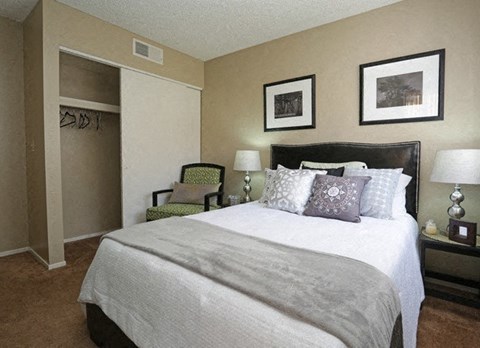 A bedroom with a large bed and a green chair.