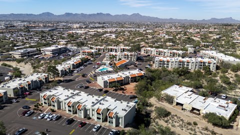 A large apartment complex is surrounded by a parking lot and other buildings.
