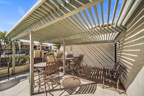 A pergola area with a table and chairs.
