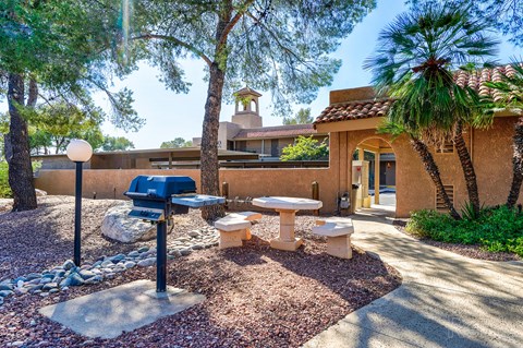 a picnic area in front of a building with a grill