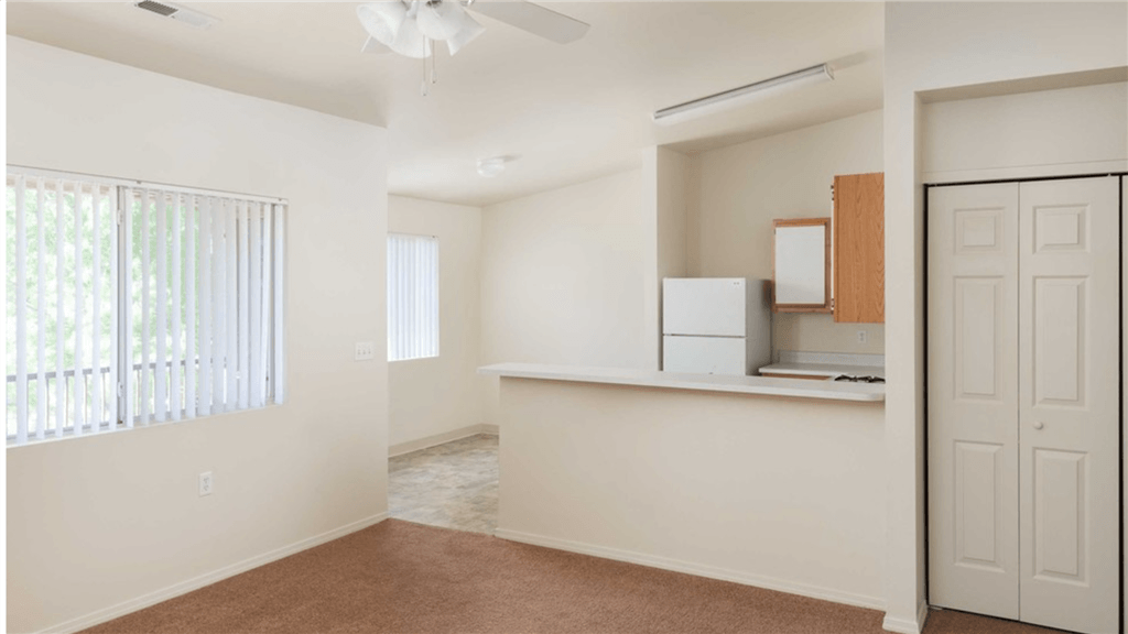 an empty living room and kitchen with a door to the closet
