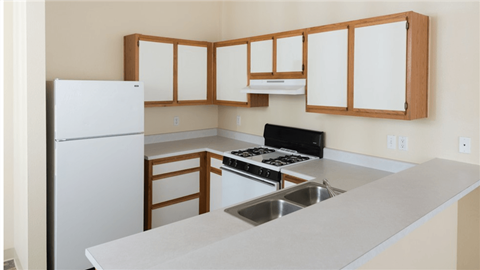 a kitchen with white counters and white appliances and wooden cabinets