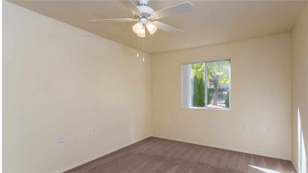 an empty living room with a ceiling fan and a window