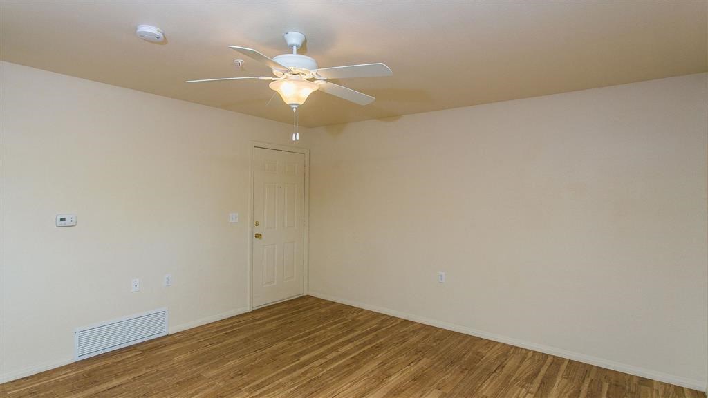 an empty room with a ceiling fan and a door