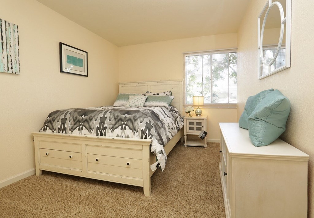a bedroom with a bed and a dresser and a window