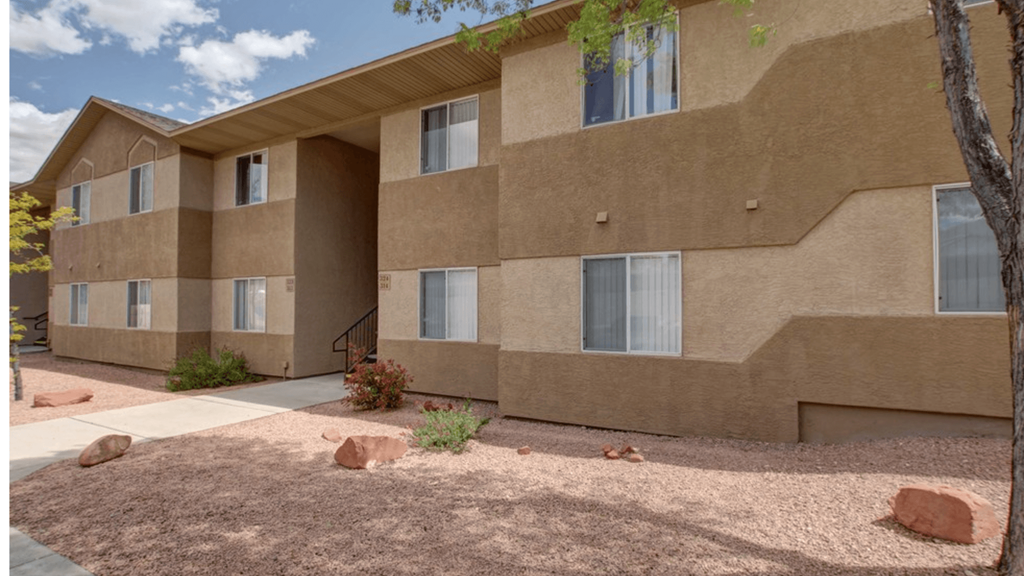 a large tan building with a sidewalk in front of it