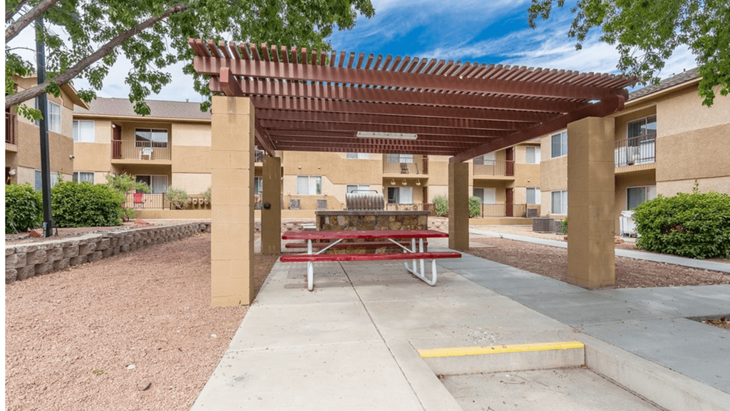 a picnic table sits under a picnic shelter in front of an apartment building