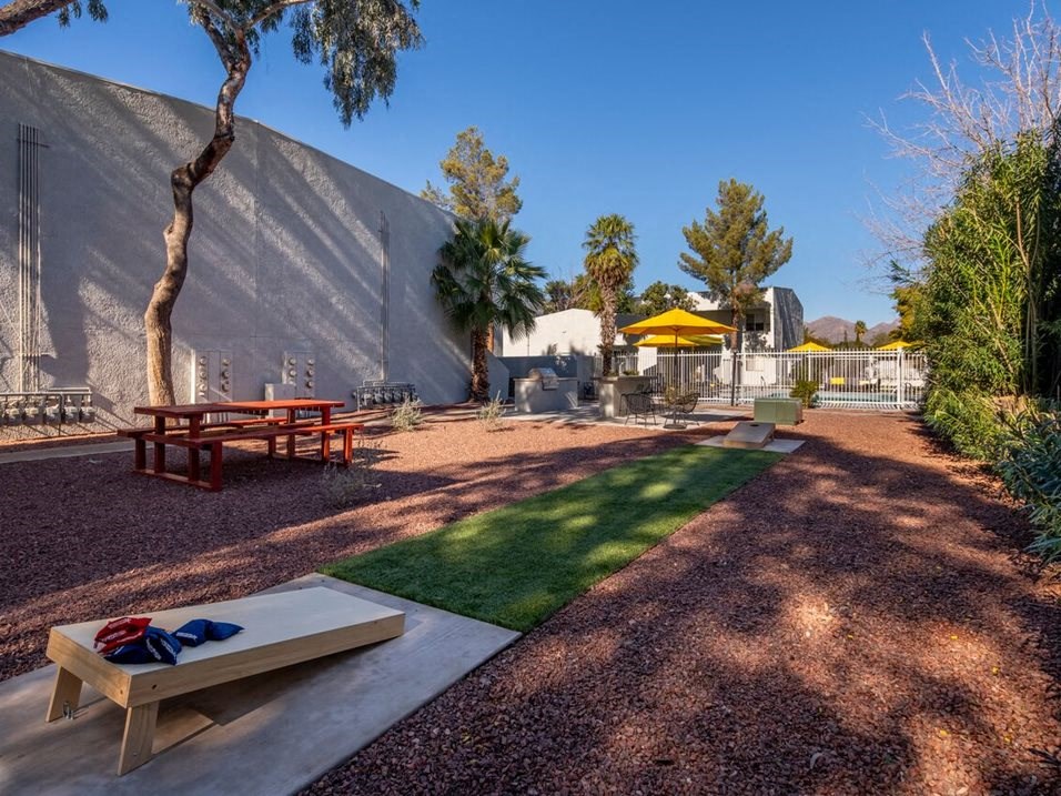 a grassy area with picnic tables and umbrellas
