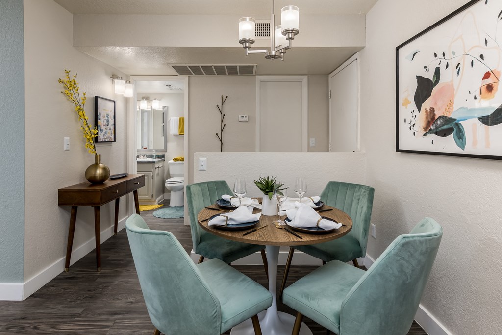 a dining area with a table and four chairs and a bathroom in the background
