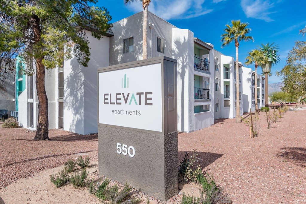 a building with a sign that says elevate apartments with palm trees in the background