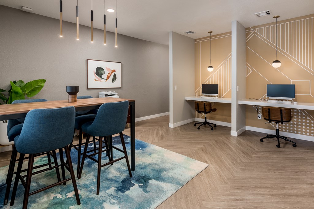 a room with a table and chairs and two computers on a desk