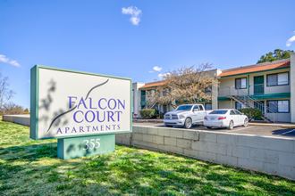 A sign for Falcon Court Apartments at the entrance to the property parking lot