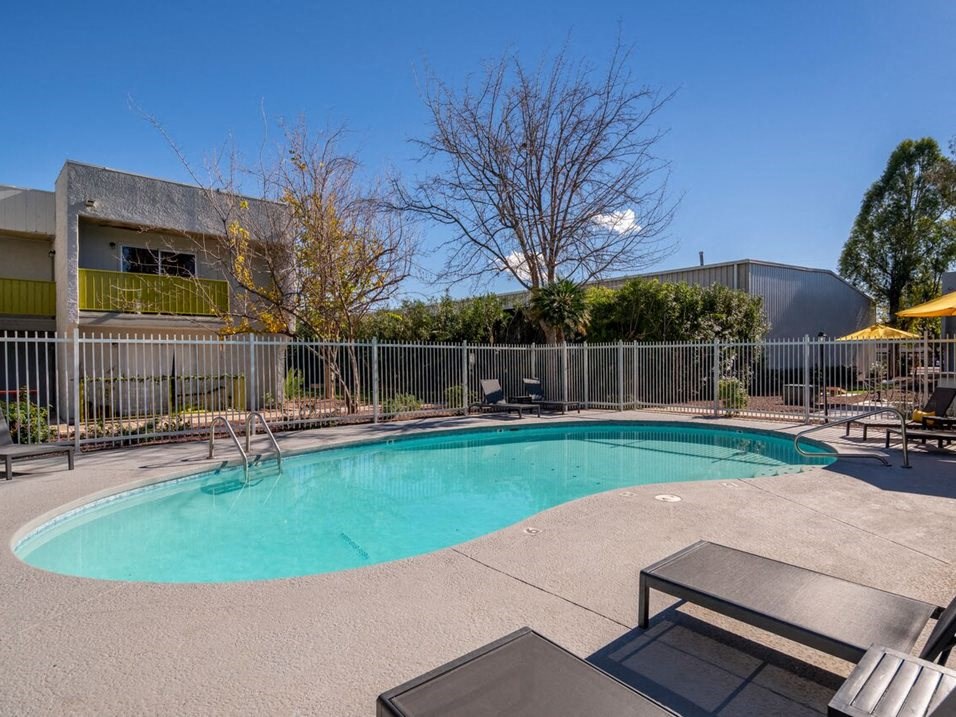 a pool with a fence around it and a building in the background