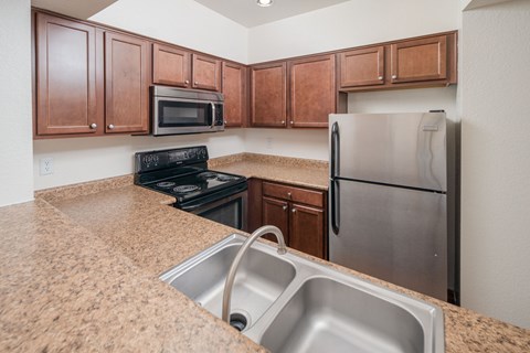 A kitchen with brown cabinets and a stainless steel refrigerator.