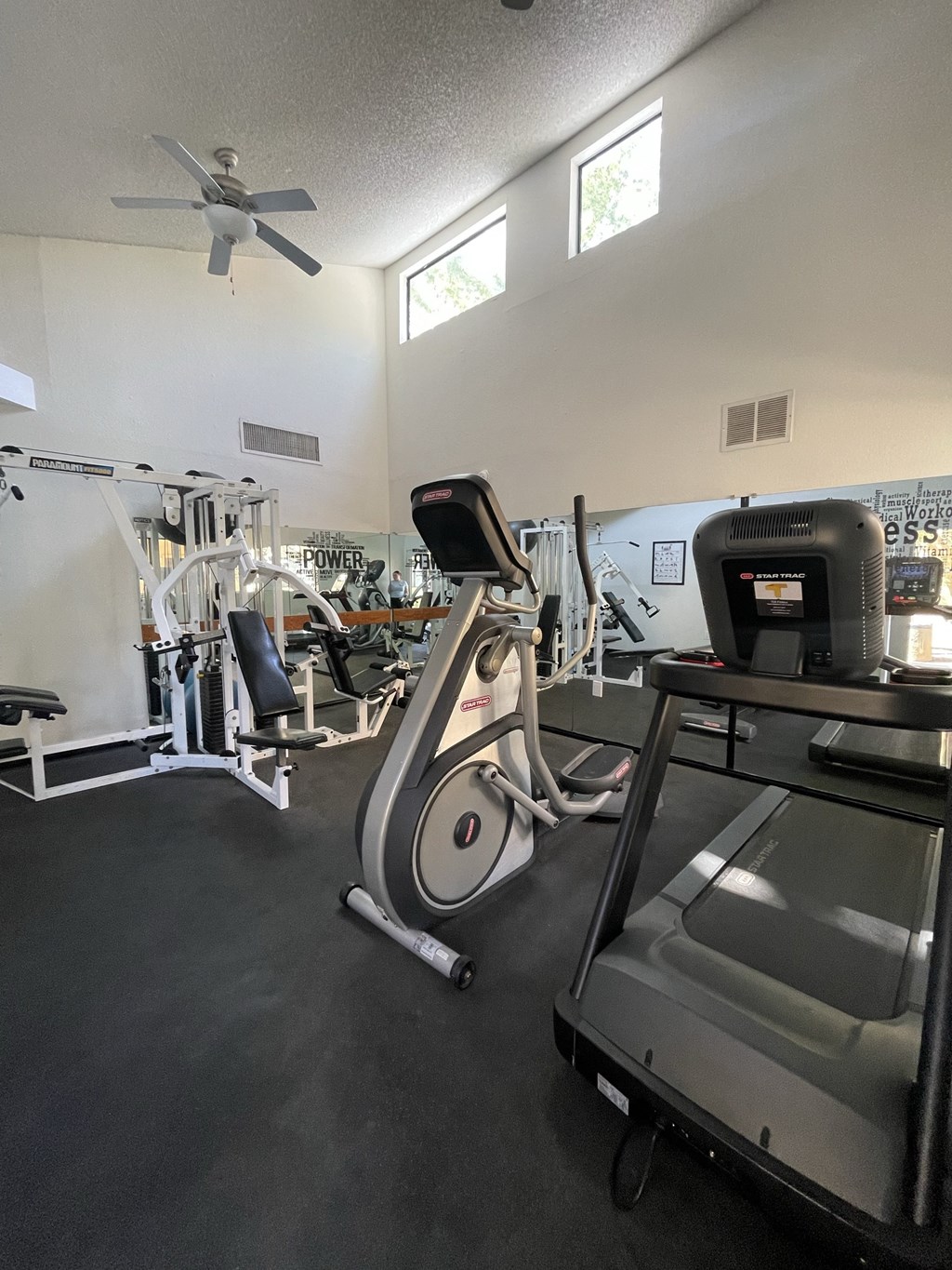 A gym with a treadmill, elliptical trainer and other exercise equipment.