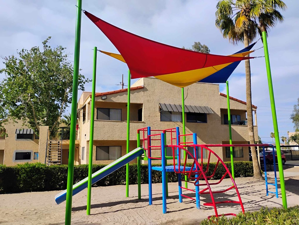 A playground with a red, yellow, blue and green slide.