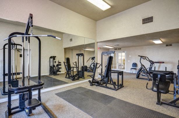 a gym with exercise equipment and mirrors on the wall
