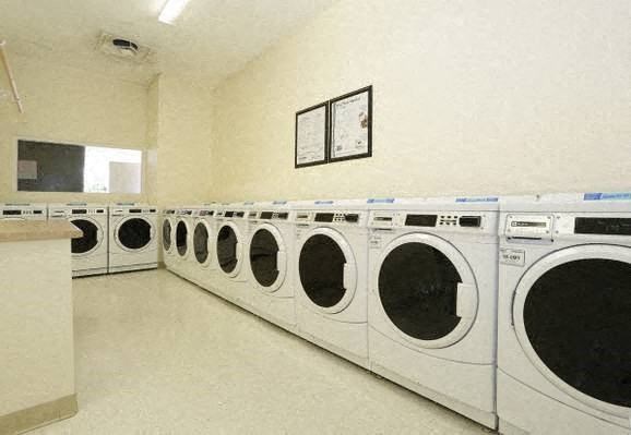 a row of white washing machines in a laundromat