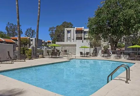 a swimming pool with chairs and umbrellas in front of a building