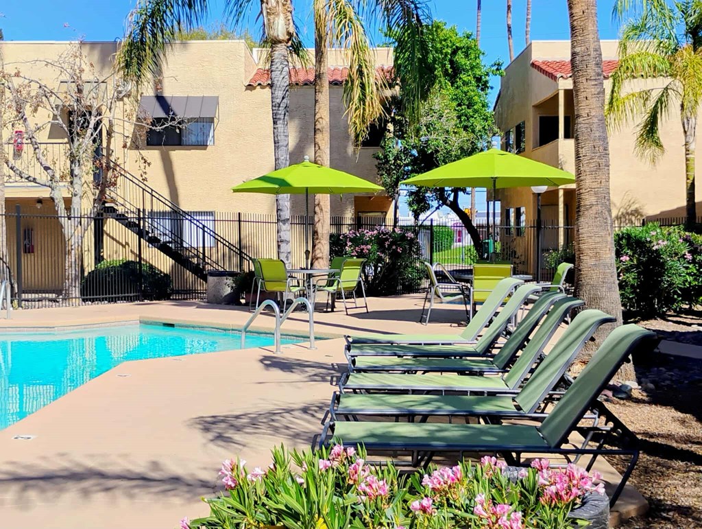 A pool area with green lounge chairs and umbrellas.