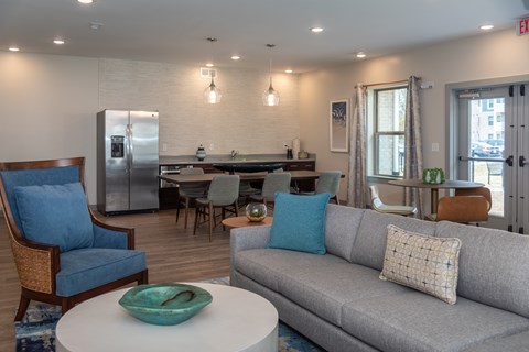 A modern living room with a grey couch, a blue chair, and a white coffee table.